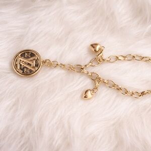 LV medallion on an empty branded Gold Chain Bracelet with Heart Charms
